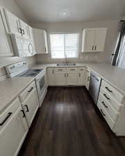 Kitchen featuring white appliances, white cabinets, light countertops, and vaulted ceiling