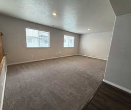 Empty room with a textured ceiling, recessed lighting, and dark colored carpet