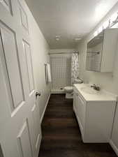 Bathroom featuring dark wood-style floors, vanity, a shower stall, and a textured ceiling
