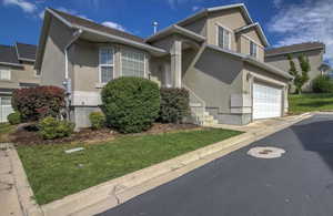 Traditional home featuring stucco siding, a front lawn, and a garage
