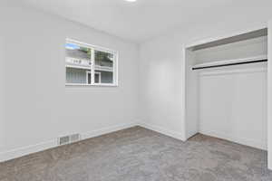 Unfurnished bedroom featuring light carpet and a closet