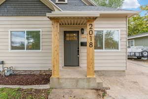 Entrance to property featuring a shingled roof