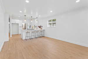 Living area with light wood finished floors, recessed lighting, and crown molding