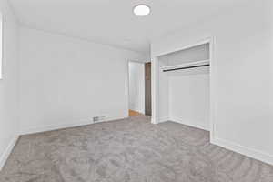 Unfurnished bedroom with light colored carpet and a closet