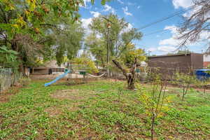 Fenced backyard featuring a playground