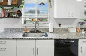 Kitchen with white cabinetry, black dishwasher, light stone countertops, and open shelves