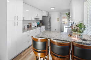 Kitchen featuring a breakfast bar, white cabinetry, a peninsula, electric range, and light wood-type flooring