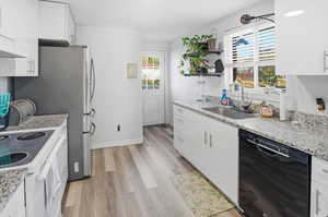 Kitchen featuring white cabinets, black dishwasher, light wood-type flooring, and open shelves
