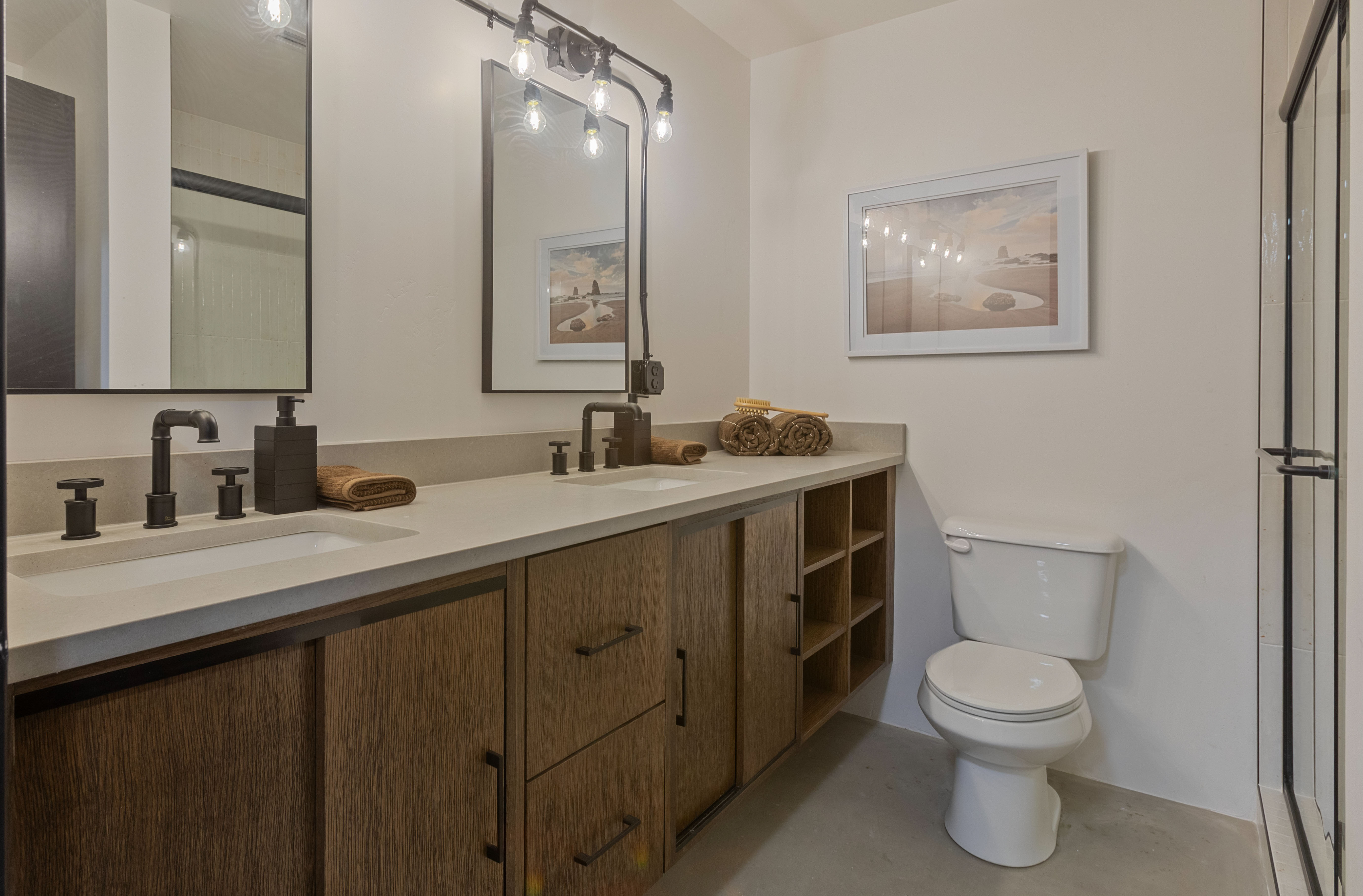 Bathroom with a stall shower, double vanity, and concrete floors