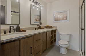 Bathroom with a stall shower, double vanity, and concrete floors