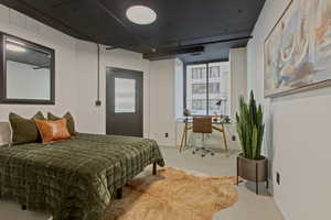 Carpeted bedroom with a desk and baseboards