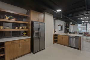 Kitchen with open shelves, brown cabinets, appliances with stainless steel finishes, decorative light fixtures, and a peninsula