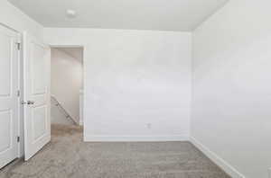 Empty room featuring light colored carpet and baseboards