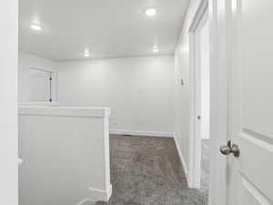 Hall featuring dark colored carpet, an upstairs landing, and recessed lighting