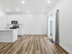 Kitchen featuring light wood-style flooring, white cabinetry, recessed lighting, appliances with stainless steel finishes, and light stone countertops