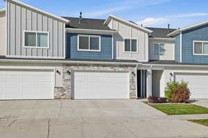 View of front facade with board and batten siding, stone siding, and concrete driveway
