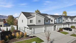 View of front facade featuring driveway, board and batten siding, a garage, a shingled roof, and a residential view