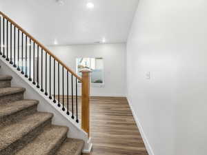 Staircase with wood finished floors and recessed lighting