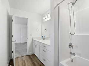 Full bath with light wood-style floors, vanity, and shower / bathtub combination