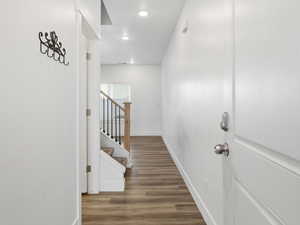 Entry with dark wood-style flooring, recessed lighting, and stairway