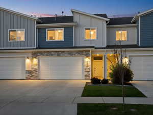 View of front of home featuring stone siding, board and batten siding, driveway, and an attached garage