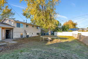 Fenced backyard featuring a trampoline