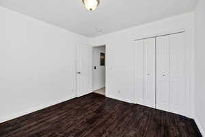 Unfurnished bedroom with dark wood-type flooring and a closet