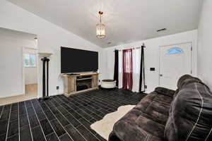 Living area with lofted ceiling, wood finish floors, healthy amount of natural light, and a fireplace