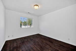 Empty room featuring dark wood-style floors and baseboards