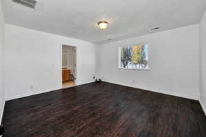 Empty room with dark wood-type flooring and baseboards