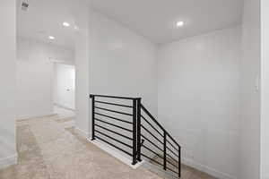 Hall featuring an upstairs landing, light carpet, and recessed lighting
