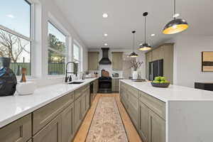 Kitchen with light stone counters, black appliances, hanging light fixtures, and gray cabinetry
