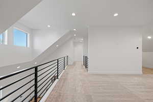 Corridor with recessed lighting and light colored carpet