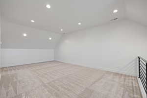 Bonus room with lofted ceiling, recessed lighting, and light carpet