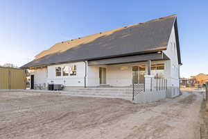 Back of house featuring roof with shingles and a patio area