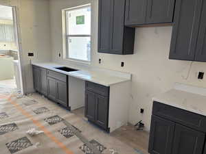 Kitchen with gray cabinetry and light stone countertops