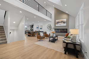 Living area featuring a glass covered fireplace, light wood-type flooring, recessed lighting, and vaulted ceiling