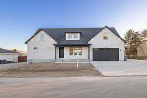 Modern inspired farmhouse with a porch, concrete driveway, stone siding, and a garage
