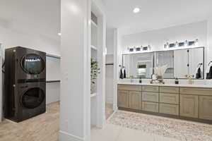 Full bath with a spacious closet, stacked washer / dryer, double vanity, and recessed lighting