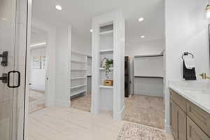 Master bathroom with a spacious closet, stacked washing machine and dryer, vanity, a stall shower, and recessed lighting
