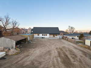 Back of property at dusk featuring a residential view, a patio area, metal shop and barn area