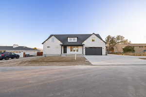 Modern farmhouse featuring driveway, covered porch, and stone siding