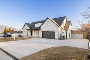 Modern farmhouse style home with covered porch, driveway, a mountain view, and stone siding