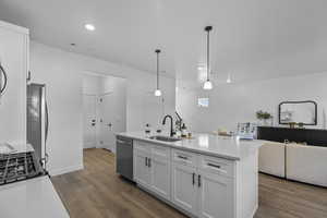 Kitchen featuring white cabinetry, pendant lighting, dark wood-style flooring, open floor plan, and a center island with sink