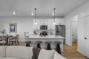 Kitchen featuring open floor plan, white cabinets, stainless steel appliances, pendant lighting, and recessed lighting