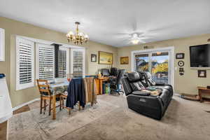 Dining area with a chandelier, a ceiling fan, a desk, and carpet