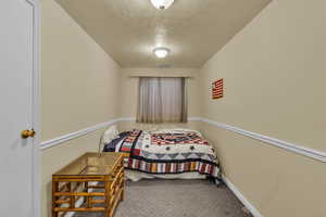 Bedroom with a textured ceiling and carpet
