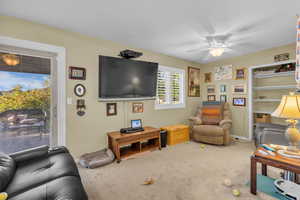 Carpeted living area with ceiling fan and baseboards