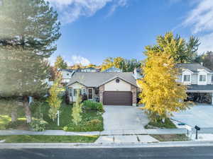 View of front of home with concrete driveway, a garage, and a front lawn