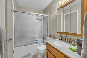 Bathroom featuring bath / shower combo with glass door and vanity